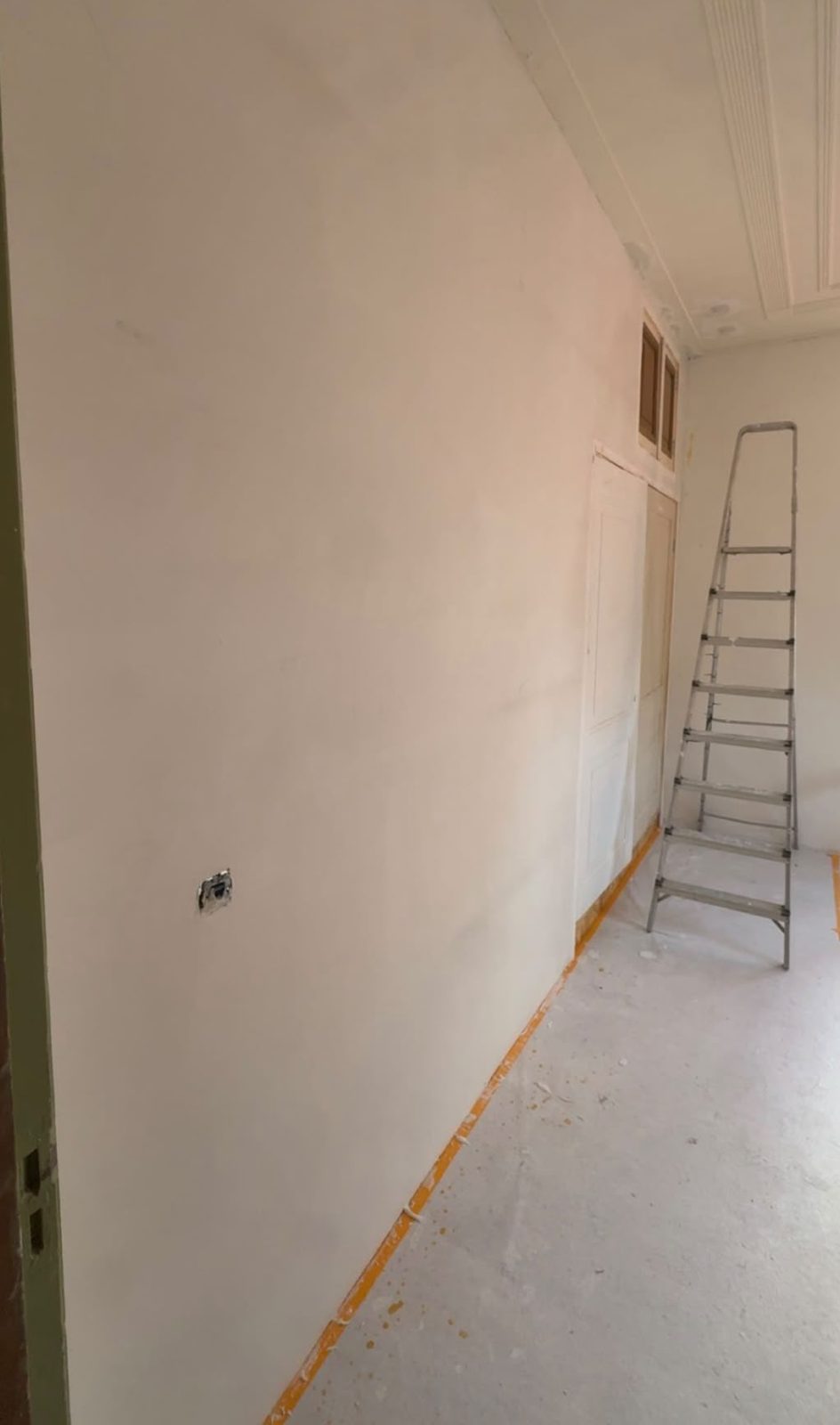 Lange gestucte wand in een gang met ladder